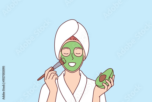 Young woman uses a green avocado face mask to hydrate her skin, treat acne, and improve her natural beauty. Concept of organic skin care, wellness routine, and healthy lifestyle choices.