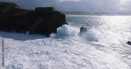 Wide view of turbulent shoreline at Nazaré, Portugal during stormy cloudy afternoon