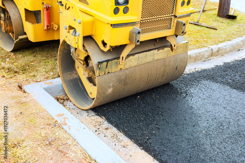 Slika na platnu Heavy road roller compacts fresh asphalt on street being constructed in quiet su