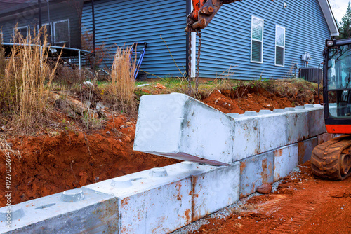 Εκτύπωση καμβά Workers use excavator machinery to position concrete blocks for retaining wall a