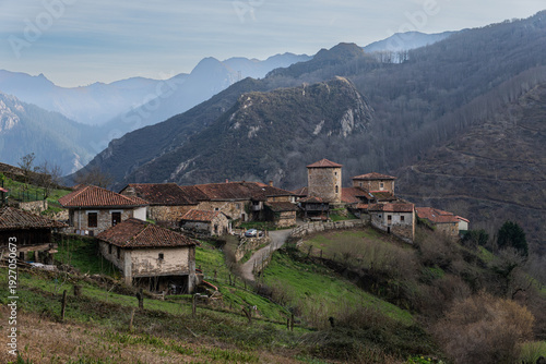 Wallpaper Mural A scenic view of the ancient stone houses and traditional hórreos (granaries) in the medieval village of Bandujo, surrounded by lush green mountains in the Proaza council, Asturias, Spain. Torontodigital.ca