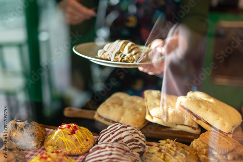 Bakery staff serving sweet pastry croissant through glass display