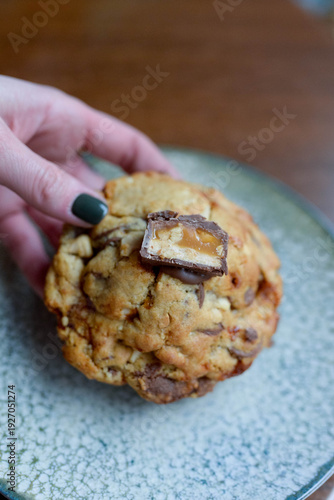 Hand holding cookie with caramel chocolate candy bar