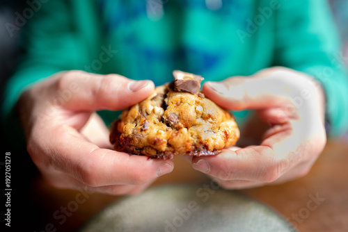 Hands holding sharing a warm chocolate chip cookie