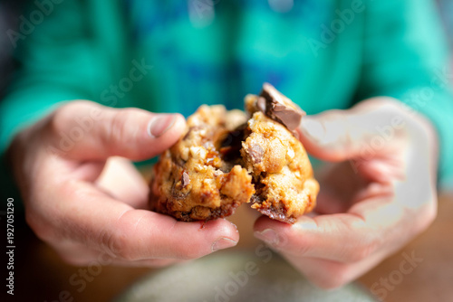 Hands breaking a warm chocolate cookie showing caramel
