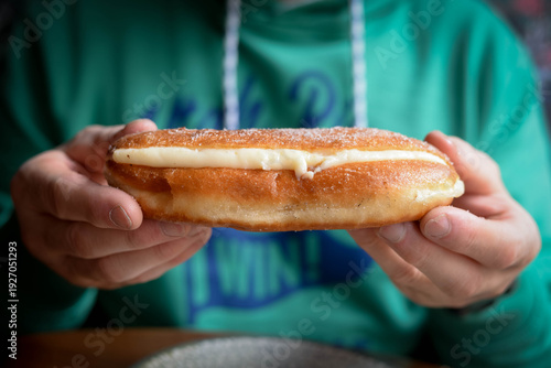 Person holding sweet cream filled pastry doughnut snack