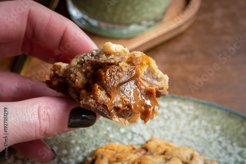 Hand holding a delicious caramel chocolate chip cookie