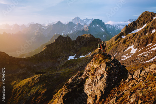 Couple friends on mountain cliff in Norway man and woman travel lifestyle together people on active summer hiking vacations tour, family climbing outdoor extreme adventure trip in Lofoten islands