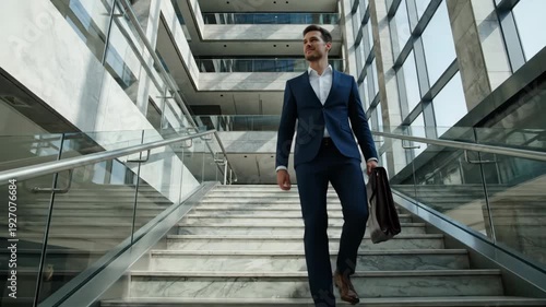 Wallpaper Mural Confident businessman in a suit walking down stairs in a modern office. Successful executive with a briefcase in a corporate building. Slow motion footage of career ambition Torontodigital.ca