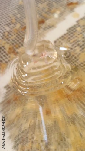 Pure acacia honey pouring through a fine mesh strainer during harvesting process