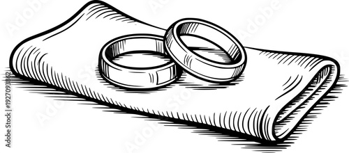 Wedding rings resting a folded cloth in a vintage engraved style marriage love