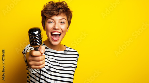 Cheerful woman with short hair laughing, holding a retro microphone forward, delivering a message or performing with excitement