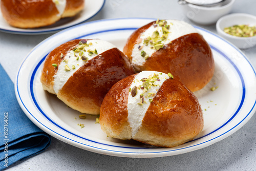 Italian maritozzo buns with whipped cream and chopped pistachios on a plate. Selection focus