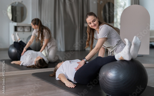 Physiotherapist Assisting Pregnant Woman With Exercise Ball Pilates Rehab Session In Modern Therapy Studio