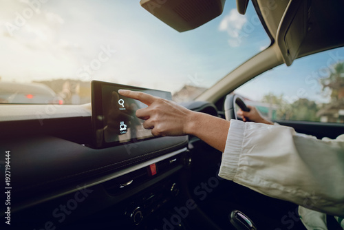Foto driver inside personal car uses the touchscreen navigation system, tapping the screen to search maps for a nearby coffee shop rest stop while traveling through city traffic