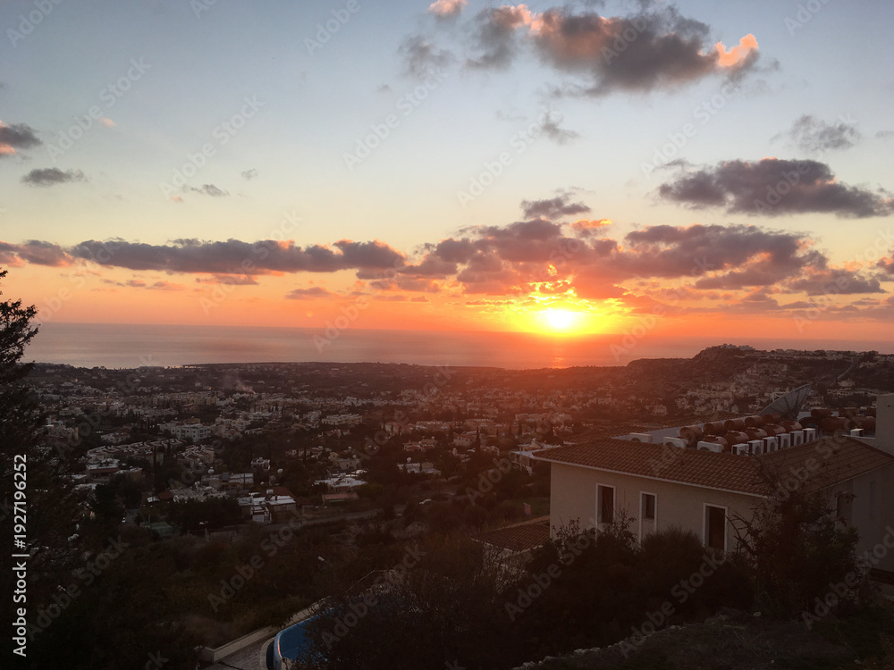 Fototapeta premium Sunset over coastal town with sea horizon in Cyprus. Evening atmosphere, travel inspiration and urban landscape panorama concept