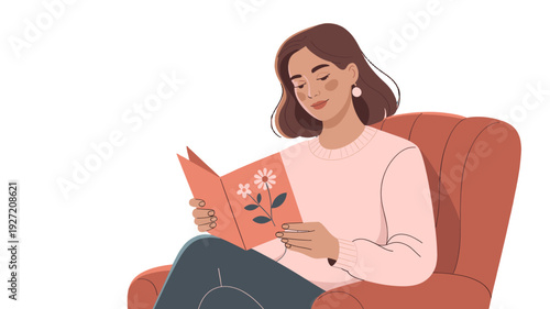 A young woman is engrossed in reading a book in a cozy armchair.