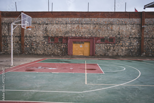 Empty Outdoor Basketball Court with Rustic Stone Wall Background – Minimal Urban Sports Scene
