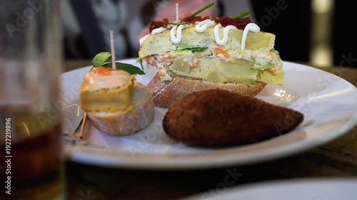 A woman turning the plate of pinchos, a famous tapas dish from Spain's Basque Country 　	