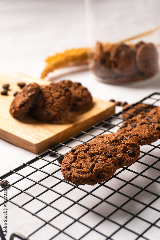 Fototapeta premium Chocolate cookies on wooden cutting board and cooling rack isolated on white background.