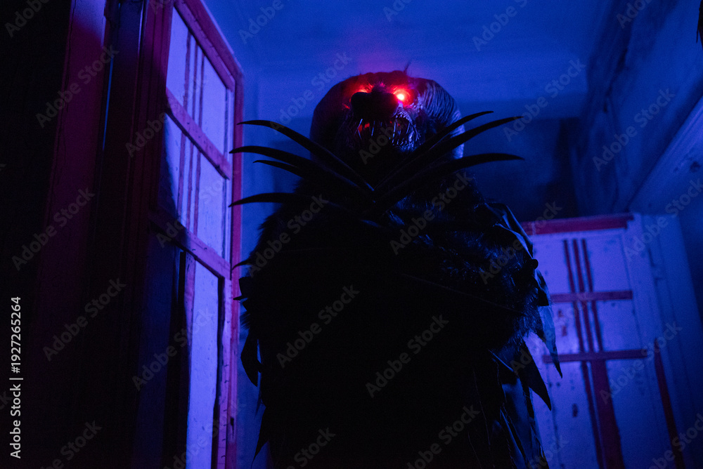 Fototapeta premium Scary Halloween Monster Costume with Glowing Red Eyes in Dark Abandoned Building