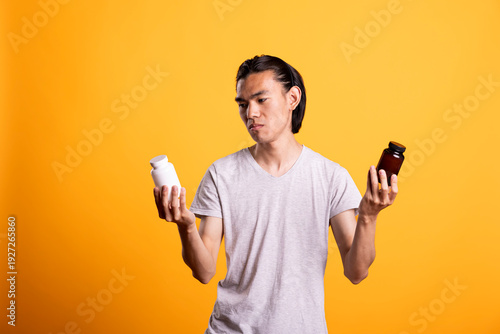 Foto Man examines two different pill bottles, feeling unsure which medication to choose