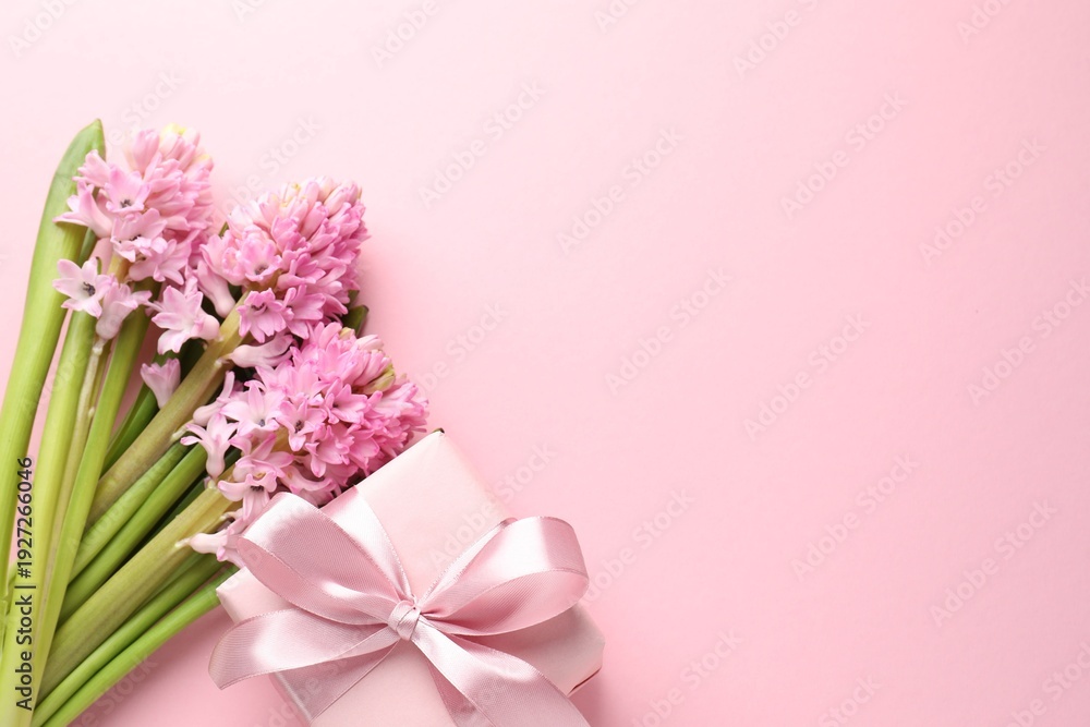 Obraz premium Beautiful hyacinth flowers and gift box on pink background, flat lay. Space for text