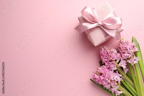 Beautiful hyacinth flowers and gift box on pink background, flat lay. Space for text