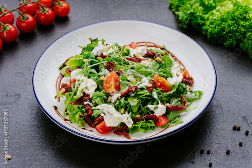 Fresh green salad with tomatoes dried tomatoes and creamy dressing on plate