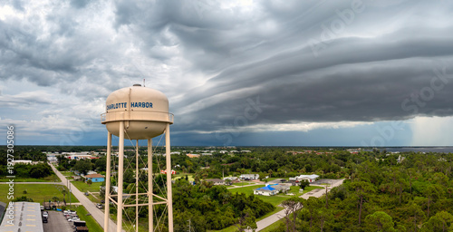 Dark storm clouds gather over Charlotte Harbor water tower in Florida during summer thunderstorm with heavy rainfall.
