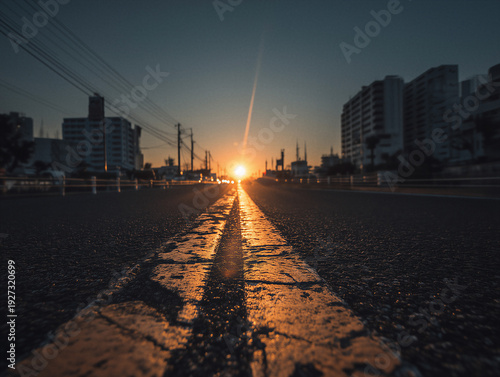 Low angle city street at sunset with leading lines and glowing road centerline