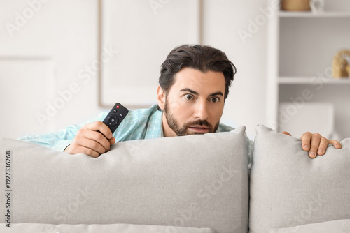 Scared young man with remot...
