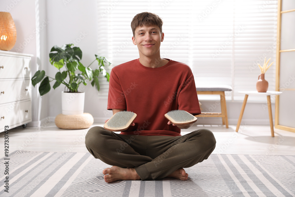 Fototapeta premium Young man with sadhu boards sitting on floor at home