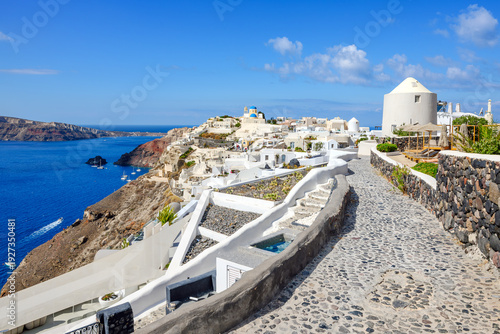 Tableau sur toile The blue dome churches rise above the whitewashed buildings and terraces overlooking the sea and volcanic caldera in Oia, Greece, on the island of Santorini