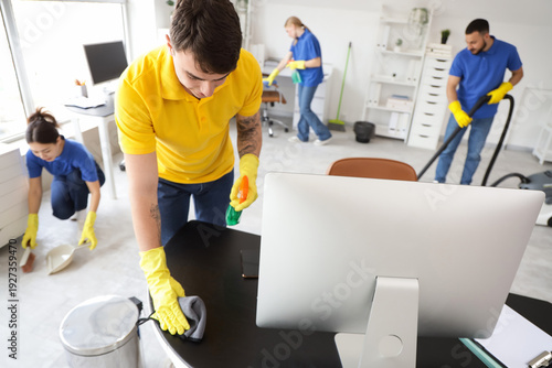 Male janitor cleaning desk ...
