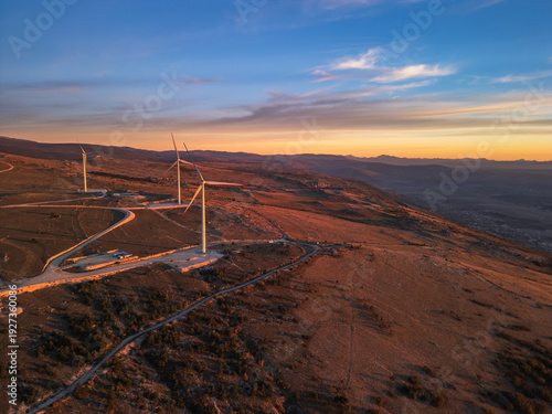 4K Aerial panorama of a large wind farm on a mountain plateau near Mostar, Bosnia and Herzegovina. Industrial landscape with multiple wind turbines at golden sunset.