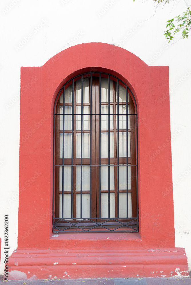 Obraz premium Classic Exterior Arch Window with Iron Bars and Red Frame Detail