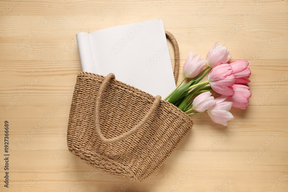 Fototapeta premium Wicker basket with blank fashion magazine and tulip flowers on wooden background. Spring season concept