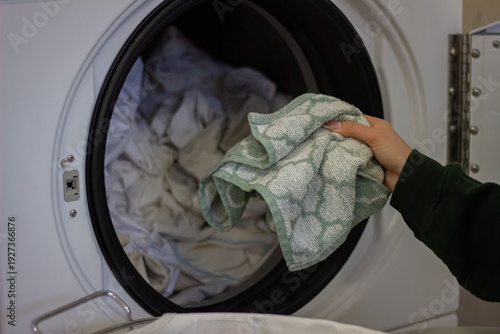Wallpaper Mural Female hand loading towel into washing machine drum close up Torontodigital.ca