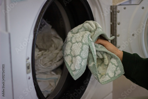 Wallpaper Mural Female hand loading towel into washing machine in laundromat close up Torontodigital.ca