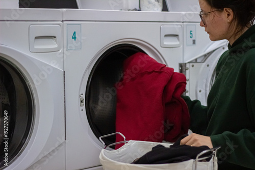 Wallpaper Mural Woman loading red blanket into washing machine in self service laundromat Torontodigital.ca