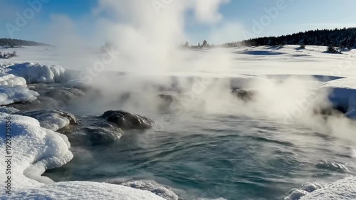 Steam rising from a hot spring in a snowy landscape.