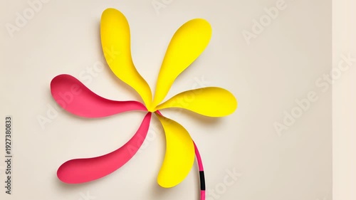 A cut-paper design featuring a flower shape with curved petals in yellow and pink hues