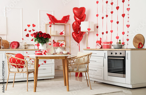 Stylish interior of light kitchen decorated for Valentine's Day with beautiful roses, gifts and tea set on table