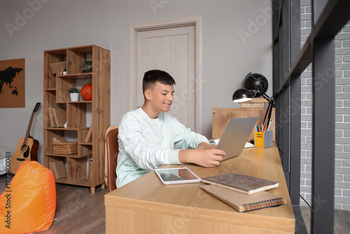 Teenage boy with laptop studying at home