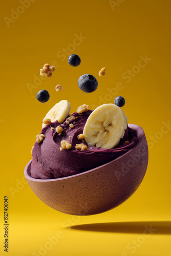 Açai bowl with some toppings suspended in the air. Yellow background 
