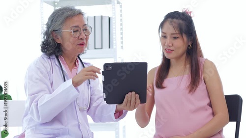 Female doctor explains the results of a prenatal checkup for an Asian woman. Health concept. Self-care during pregnancy.