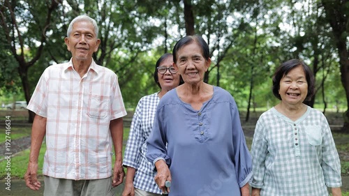 A group of elderly people walk in the park for health, smiling happily. Retirement life. Health insurance.