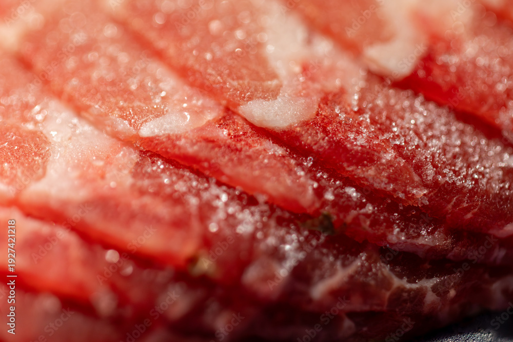 Obraz premium The delicate marbled texture of bright red frozen pork slices