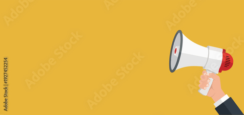 Hand holding a megaphone announcing important news or making a public announcement against a plain yellow background, communication concept